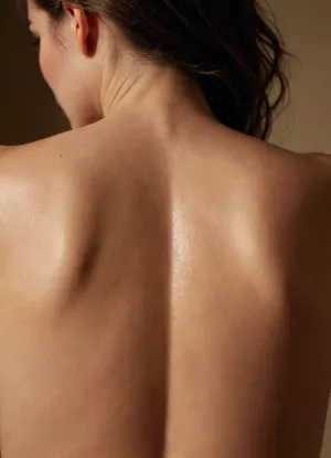 A closeup of a woman’s back, Warm cinematic lighting. Her skin is covered in Goosebumps, <lora:Sweaty_Realism_4-000006:.8>