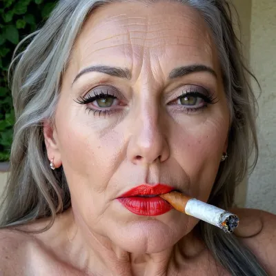 Una mujer europea de 50 años con grandes tetas y un estómago plano fuma un cigarrillo mientras disfruta de una expresión de orgasmo en su cara