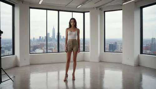 full body view, 20-year-old brunette standing in front of a large windows with big city outside facing viewer, professional casting photo studio, studio, stud10, white, screen, <lora:stud10:.8>