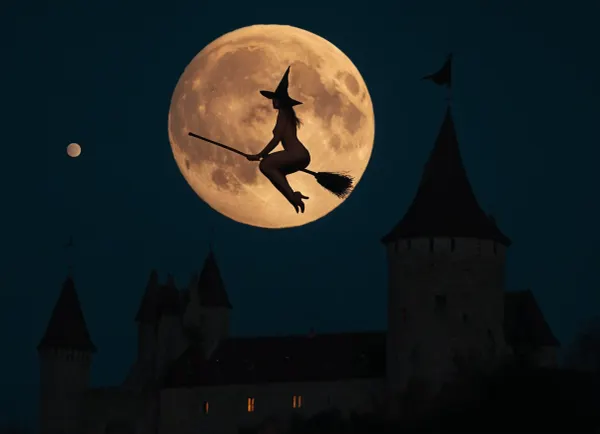 Una giovane strega si alza sopra un castello medievale, la sua scopa scivola senza sforzo attraverso l'aria